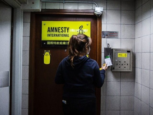 A woman is seen at the entrance to Amnesty International offices in Hong Kong on October, 2021, as the Human Rights organisation announces it will be closing its offices by the end of 2021 citing Beijings enacted national security law as a reason. (Photo by ISAAC LAWRENCE / AFP) (