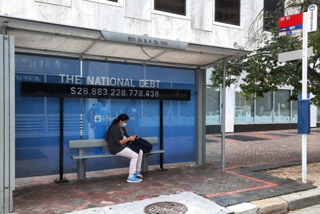 A sign at bus stop shows the amount of the US national debt in Washington on October 25, 2