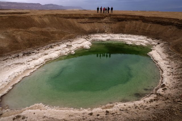 Hikers walk next to sinkholes in the southern part of the Dead Sea