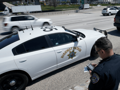 In this April 23, 2021 file photo, California Highway Patrol officer Troy Christensen runs a driver's license after stopping a motorist along Interstate 5 who was suspected of speeding in Anaheim, Calif. The number of highway deaths in 2020 was the greatest in more than a decade even though cars …