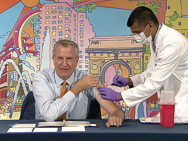 In this image from video, New York Mayor Bill de Blasio, left, receives a COVID-19 Moderna