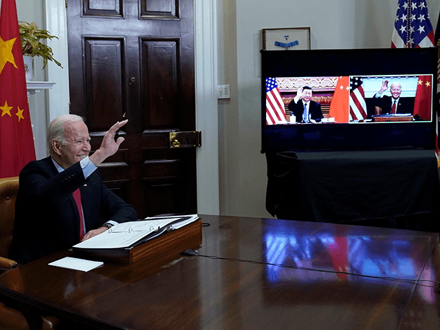 President Joe Biden, left, waves hello as he meets virtually with Chinese President Xi Jinping, on screen, from the Roosevelt Room of the White House in Washington, Monday, Nov. 15, 2021. (AP Photo/Susan Walsh)