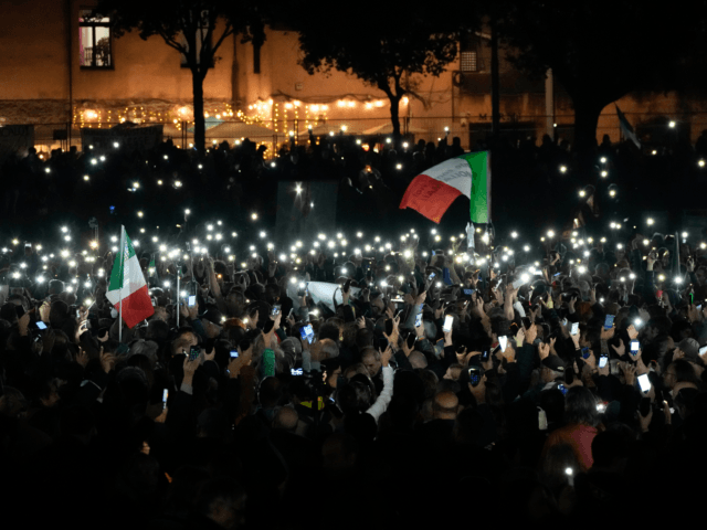 Demonstrators listen to speakers and show their mobile phones during a protest against restrictions for the unvaccinated, at Rome Circus Maximus, Saturday, Nov. 20, 2021. With infections spiking again despite nearly two years of restrictions, the health crisis increasingly is pitting citizen against citizen — the vaccinated against the unvaccinated. …