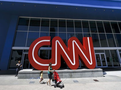 Pedestrians pass the entrance to CNN headquarters, Tuesday, Aug. 26, 2014, in Atlanta. The corporate parent of CNN, TNT and TBS on Tuesday offered voluntary buyouts to 600 veteran employees, part of an overall cost-cutting effort at the Atlanta-based broadcasting company founded by Ted Turner. The offer went out to …