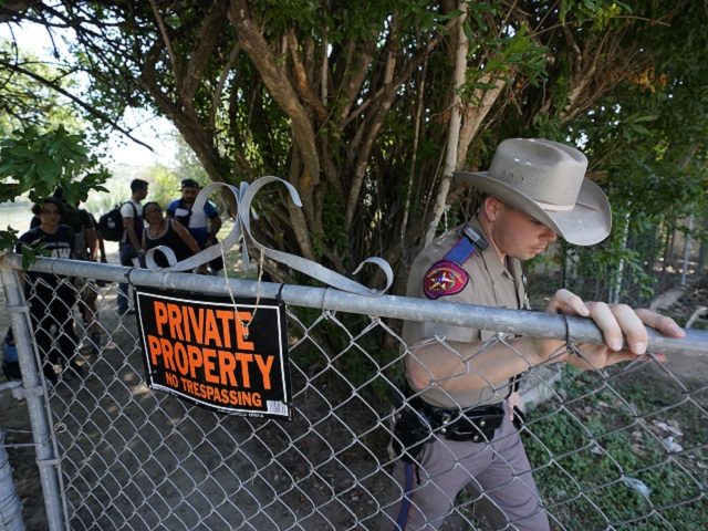 A Texas Department of Public Safety officer directs a group of migrants who crossed the bo