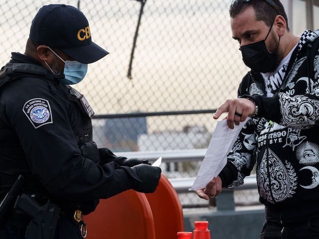 A man shows his proof of vaccination to a Customs and Border Protection agent atop the Paso Del Norte Port of Entry in downtown El Paso, Texas on November 8, 2021. (Paul Ratje/AFP via Getty Images)