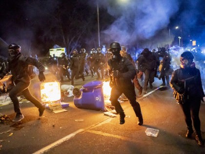 Portland police officers chase demonstrators after a riot was declared during a protest against the killing of Daunte Wright on April 12, 2021 in Portland, Oregon. Wright, a Black man whose car was stopped in Brooklyn Center, Minnesota on Sunday reportedly for an expired registration, and not far from where …