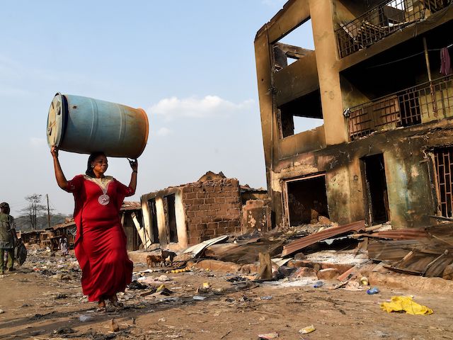 A woman carries plastic drum salvaged from burnt shop after deadly ethnic clashes between the northern Fulani and southern Yoruba traders at Shasha Market in Ibadan, southwest Nigeria, on February 15, 2021. - Nigerian President vowed to protect all religious and ethnic groups in the country after deadly clashes erupted between different communities at a market in the southwest over the weekend. Long-standing rivalry over access to land and resources between northern Fulani herders and southern Yoruba farmers are behind renewed ethnic tensions across the south. (Pius Utomi Ekpei/AFP via Getty Images)