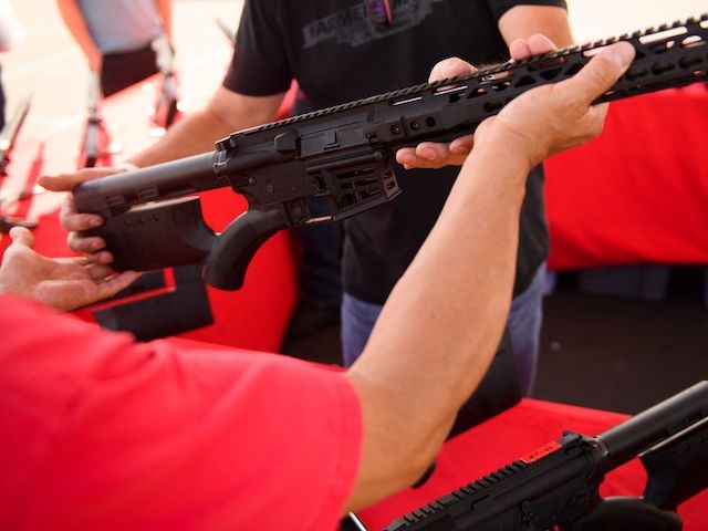 A clerk hands a customer a California legal, featureless AR-15 style rifle from TPM Arms LLC on display for sale at the company's booth at the Crossroads of the West Gun Show at the Orange County Fairgrounds on June 5, 2021 in Costa Mesa, California. (Patrick T. Fallon/AFP via Getty Images)