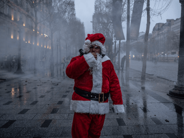 PARIS, FRANCE - DECEMBER 15: A man dressed as Santa Claus walks along the street after the Yellow Vests march December 15, 2018 in Paris, France. The protesters gathered in Paris for a 5th weekend despite President Emmanuel Macron's recent attempts at policy concessions, such as a rise in the …