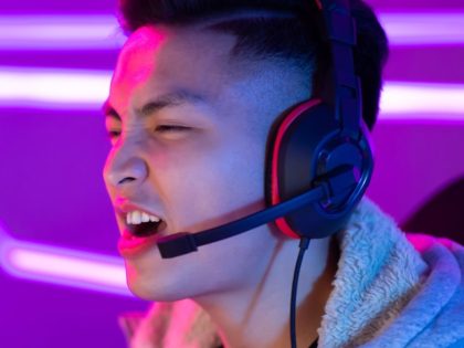 Excited angry shocked young asian gamer playing in Online Video Game and screaming looking on a screen