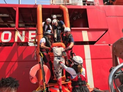 Crew members of the 'Ocean Viking' rescue ship, operated by French NGOs SOS Mediterranee and Medecins sans Frontieres (MSF), help a woman climb on board from a "rhib", an inflatable rescue dinghy, where she will be registered and taken in charge by a medical team on August 9, 2019, during …