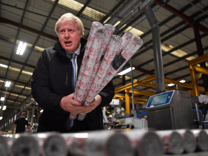 Britain's Prime Minister and Conservative party leader Boris Johnson gestures with some rolls of Christmas wrapping paper during a visit to IG Design Group, wrapping paper designer and producer in Hengoed, south Wales on December 11, 2019, the final day of campaigning for the general election. - Britain will go …