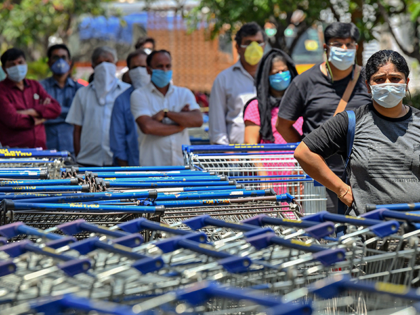 People queue to buy supplies outside a supermarket during a government-imposed nationwide