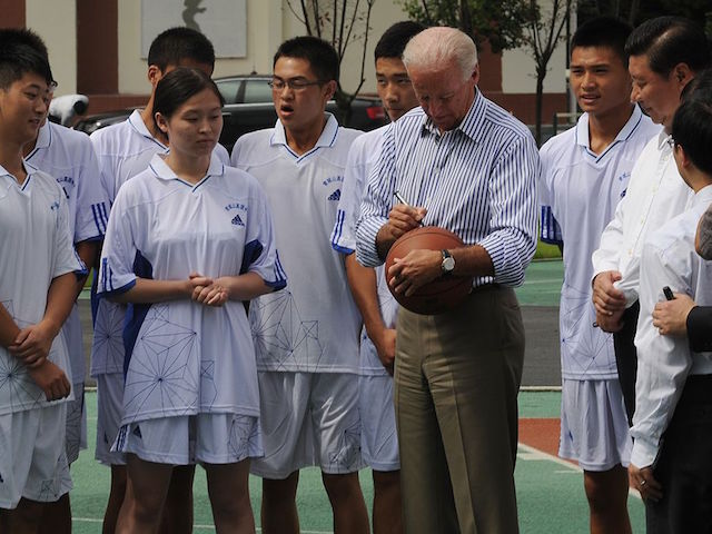 US Vice President Joe Biden (C-R) signs a basketball accompanied by Chinese Vice President Xi Jinping (2nd-R) and students at Dujiangyan Qingchengshan high school outside Chengdu in China's southwest province of Sichuan on August 21, 2011. Biden said that the world's biggest economy has never defaulted on its debt and never would, during a visit aimed at boosting Chinese confidence in the US economy. AFP PHOTO/Peter PARKS (Photo credit should read PETER PARKS/AFP via Getty Images)