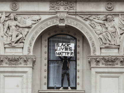 LONDON, ENGLAND - JUNE 03: A protester holds up a 'Black Lives Matter' sign as they stand on a windowsill of the Foreign and Commonwealth Office during the Black Lives Matter protest on Whitehall on June 3, 2020 in London, United Kingdom. The death of an African-American man, George Floyd, …