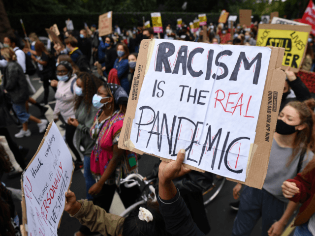 People hold up placards as they take part in the inaugural Million People March march from Notting Hill to Hyde Park in London on August 30, 2020, to put pressure on the UK Government into changing the "UK's institutional and systemic racism". - The march is organised by The Million …