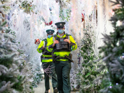Police officers wearing a face mask or covering due to the COVID-19 pandemic, walk past a display of Christmas trees in Belfast on November 27, 2020, as stricter restrictions come in to force to help stem the spread of the novel coronavirus. - Northern Ireland shops, pubs and restaurants will …