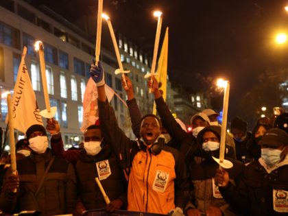 Protesters hold candles during a demonstration for the regularisation of migrants at the o