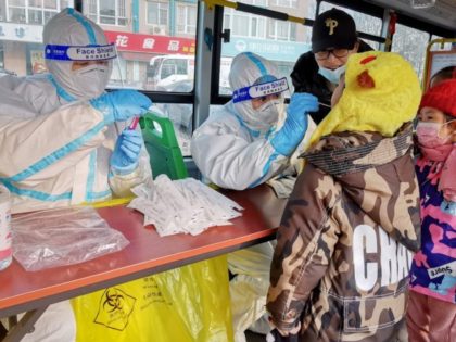 A health worker (C) in a protective suit takes a swab from a child to test for the Covid-19 coronavirus as the city carries out a mass testing program after new confirmed cases were found in Dalian, in northeastern China's Liaoning province on December 23, 2020. (Photo by STR / …