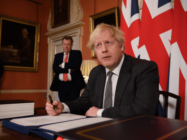 UK chief trade negotiator, David Frost (L) looks on as Britain's Prime Minister Boris Johnson (R) signs the Trade and Cooperation Agreement between the UK and the EU, the Brexit trade deal, at 10 Downing Street in central London on December 30, 2020. - British Prime Minister Boris Johnson on …