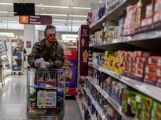 TUNBRIDGE WELLS, ENGLAND - JANUARY 12: A man wearing a Union Jack flag design face mask shops in a Sainsburys supermarket on January 12, 2021 in Tunbridge Wells, United Kingdom. In response to government ministers voicing concerns about the public's behaviour in supermarkets, Sainsbury's and Morrisons have both announced they …