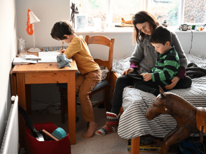 Seven-year-old Leo (L), and four-year-old Espen (R) are watched by their mother Moira as they complete their remote learning tasks, set by their local primary school after they were made to close due to COVID-19, in Marsden, northern England on January 21, 2021. - Schools and colleges across Britain closed …