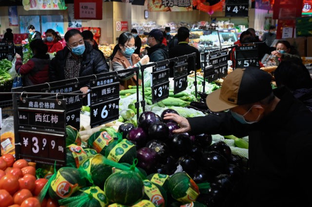 People select vegetables at a supermarket in Beijing on February 10, 2021. (Photo by WANG