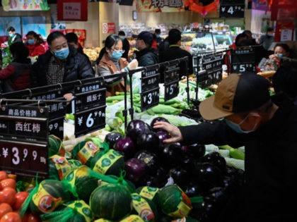 People select vegetables at a supermarket in Beijing on February 10, 2021. (Photo by WANG