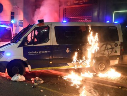 A Molotov cocktail bursts into flames next to a municipal police vehicle during a demonstr