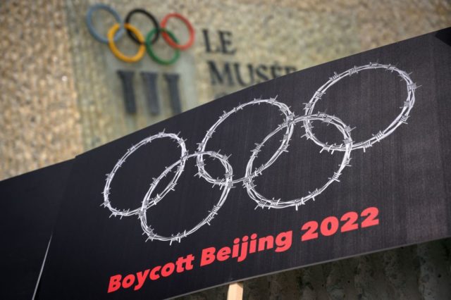 This photograph taken on June 23, 2021 shows a placard representing barber wire shaping and Olympics Rings are seen next to a sign of the Olympics Museum during a protest organised by Tibetan and Uyghur activists against Beijing 2022 Winter Olympics, in Lausanne as some 200 participants took part to …