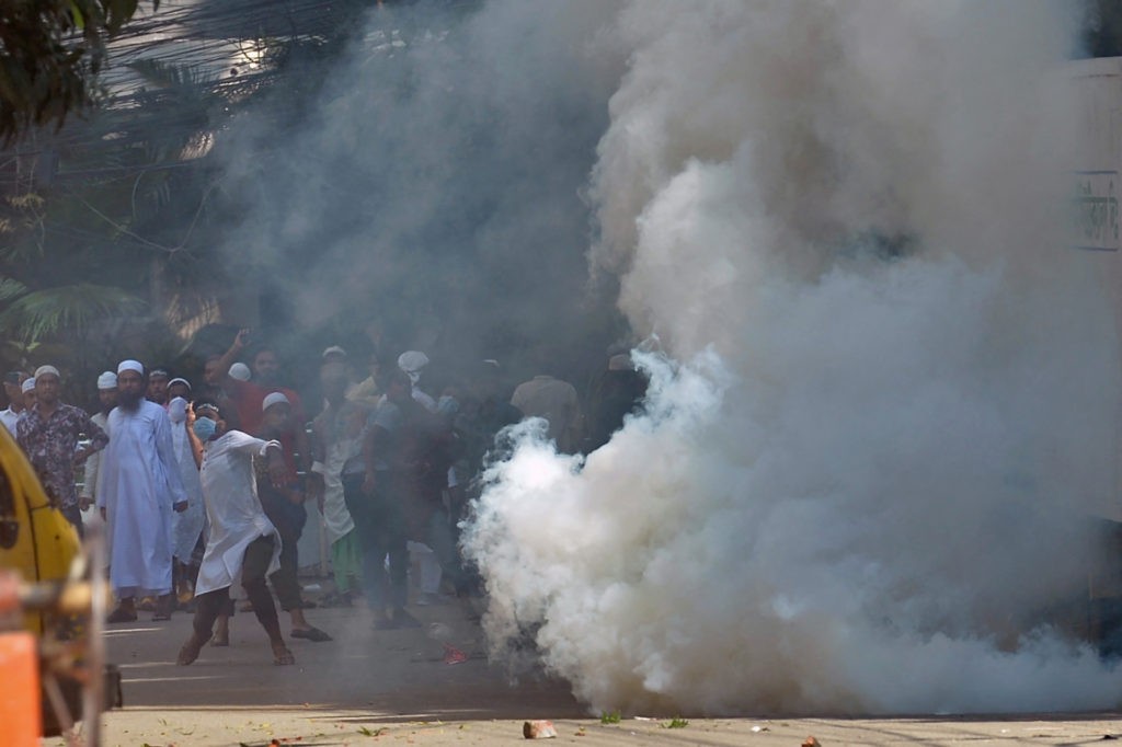 Protesters pelt stones towards police amid tear gas during a demonstration after the Friday prayers near a mosque in Dhaka on October 15, 2021, as protests began on October 13 after footage emerged of a Koran being placed on the knee of a figure of a Hindu god during celebrations for the Hindu festival of Durga Puja. (Photo by Munir Uz zaman / AFP) (Photo by MUNIR UZ ZAMAN/AFP via Getty Images)
