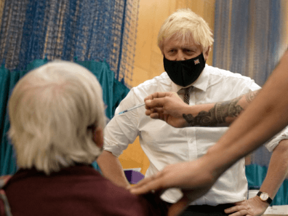 British Prime Minister Boris Johnson watches as 88-year-old Nitza Sarner receives a Pfizer-BioNTech booster vaccination as he visits a Covid-19 vaccination centre at Little Venice Sports Centre in London on October 22, 2021. - Daily virus cases in the UK on October 22 soared to over 50,000 a day for …