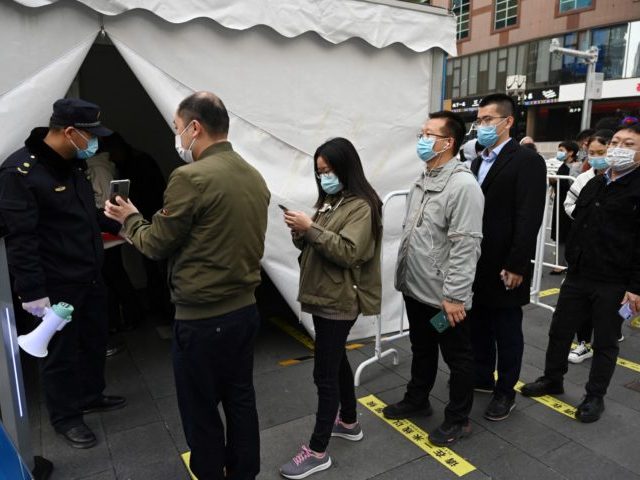 People line up to get a booster shot of the Covid-19 coronavirus vaccine in a tent set up outside a shopping mall in Beijing on November 1, 2021. (Photo by GREG BAKER / AFP) (Photo by GREG BAKER/AFP via Getty Images)