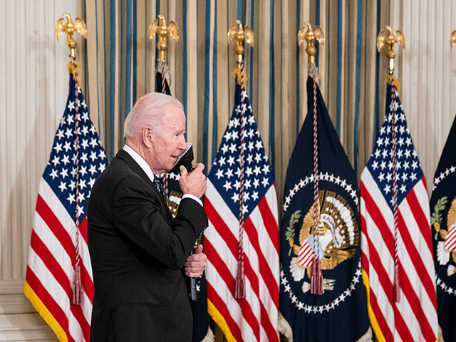 U.S. President Joe Biden removes a protective face mask before delivering remarks on the O