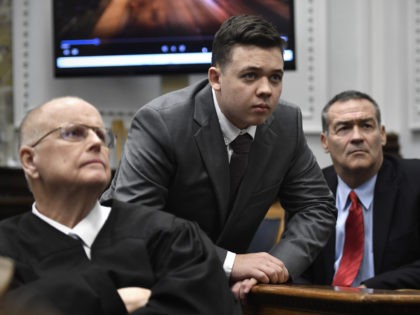 KENOSHA, WISCONSIN - NOVEMBER 12: Judge Bruce Schroeder, left, Kyle Rittenhouse, center, along with his attorney Mark Richards watch an evidence video in question on a 4k television screen during proceedings at the Kenosha County Courthouse on November 12, 2021 in Kenosha, Wisconsin. Rittenhouse is accused of shooting three demonstrators, …