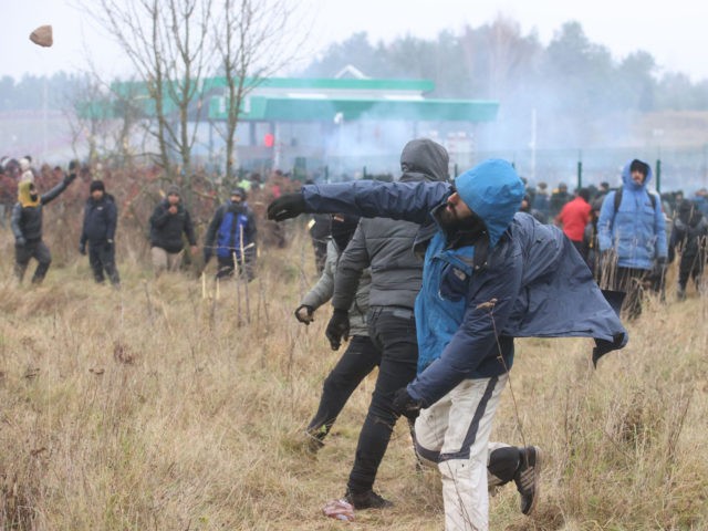 TOPSHOT - Migrants throw stones at Polish law enforcement officers as they attempt to cross into Poland at the Bruzgi-Kuznica border crossing on the Belarusian-Polish border on November 16, 2021. - - Belarus OUT (Photo by Leonid SHCHEGLOV / BELTA / AFP) / Belarus OUT (Photo by LEONID SHCHEGLOV/BELTA/AFP via …