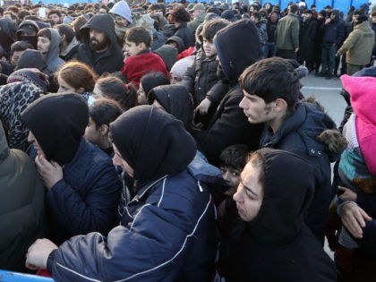 Migrants line up outside the transport and logistics centre near the Bruzgi border point o