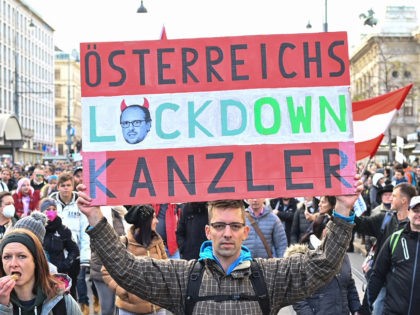 A demonstrator holds up a placard which reads "Austria's Lockdown Chancellor" as he takes part in a rally held by Austria's far-right Freedom Party FPOe against the measures taken to curb the coronavirus (Covid-19) pandemic, at Maria Theresien Platz square in Vienna, Austria on November 20, 2021. - Austria will …