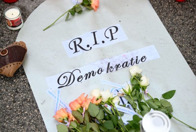 Candles and a poster with the lettering 'Rest in peace democracy' are seen at Mozart Square in Salzburg, Austria on November 22, 2021, as the country returns to a nationwide partial lockdown during the ongoing coronavirus (Covid-19) pandemic. - The Alpine nation is also imposing a sweeping vaccine mandate from …