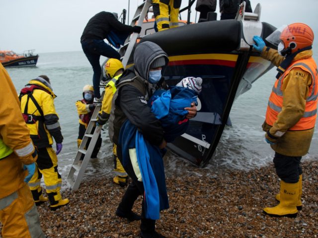 TOPSHOT - Migrants are helped ashore from a RNLI (Royal National Lifeboat Institution) lifeboat at a beach in Dungeness, on the south-east coast of England, on November 24, 2021, after being rescued while crossing the English Channel. - The past three years have seen a significant rise in attempted Channel …