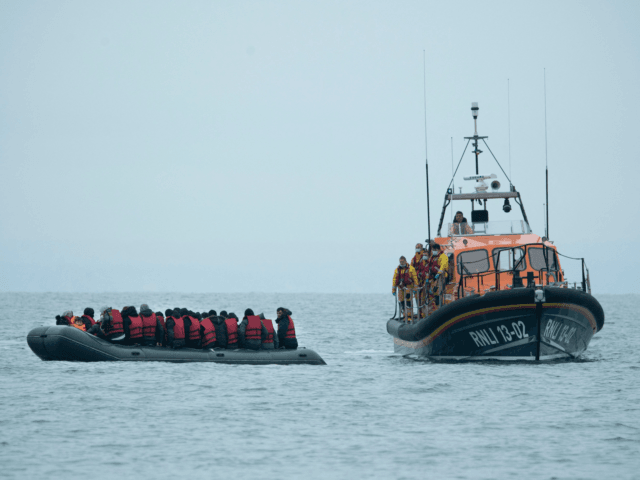 Migrants are helped by RNLI (Royal National Lifeboat Institution) lifeboat before being ta