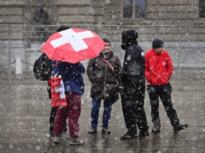 Protesters against the current measures to tackle the spread of the coronavirus demonstrate under snow in front of the Swiss House Parliament following the result a nationwide vote on a Covid-19 law, in Bern on November 28, 2021. - Swiss voters have firmly backed the law behind the country's Covid …