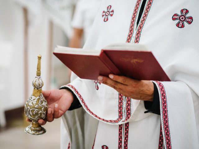 The priest holds a bible in the church. Holy sacramental event. Close up.