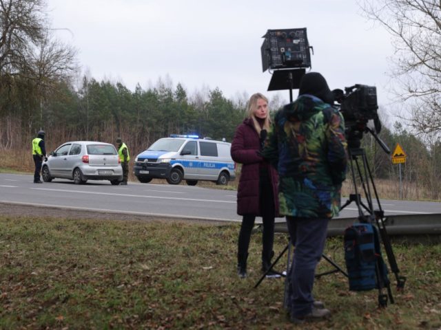KUZNICE, POLAND - NOVEMBER 15: A television journalist reports from a police checkpoint on a road leading to the border to Belarus on November 15, 2021 near Kuznice, Poland. Poland and Belarus are currently in a standoff over thousands of migrants, many of them from Iraq, Syria and Yemen, who …