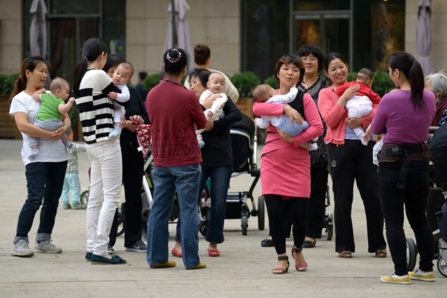 A group of women hold babies gathering at a residential area in Beijing on September 16, 2