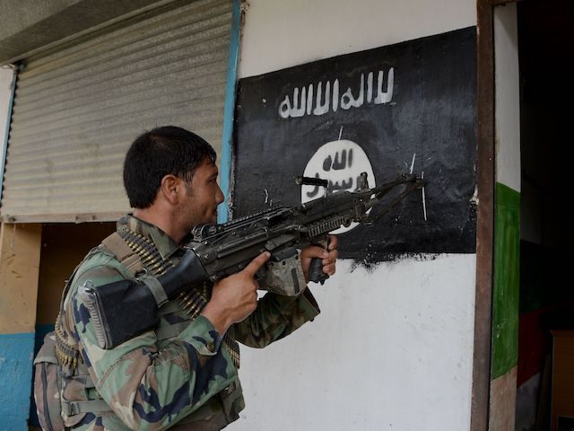 An Afghan soldier points his gun at an Islamic State group banner as he patrols during ong