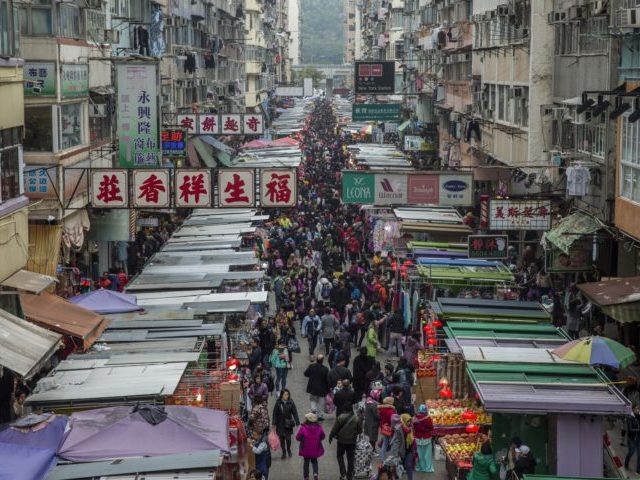 TOPSHOT - People (C) walk through a market crowded with shoppers in the Kowloon district of Hong Kong on February 4, 2018, ahead of the coming Lunar New Year.