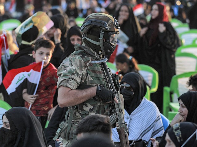 A member of Iraq's Hashed al-Shaabi (Popular Mobilisation) paramilitary forces stands guard during an election rally for the "Asaib Ahl al-Haq" movement in the capital Baghdad, on October 7, 2021. - More than 25 million Iraqis are eligible to vote for a new parliament on October 10, in the fifth …