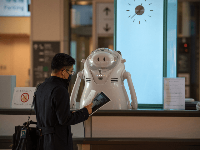 TOKYO, JAPAN - NOVEMBER 30: A man talks to a robot on an information desk at Haneda Airpor